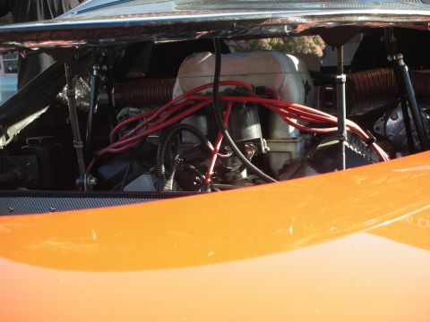 1998 Ford Crown Victoria - Engine bay of an orange car viewed through the rear deck, showing a V8 wrapped in red spark-plug wires.