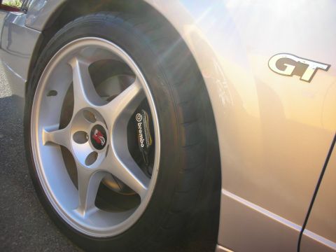1998 Ford Crown Victoria - Close-up of a silver five-spoke wheel with a yellow Brembo brake caliper and a GT badge on the adjacent fender.