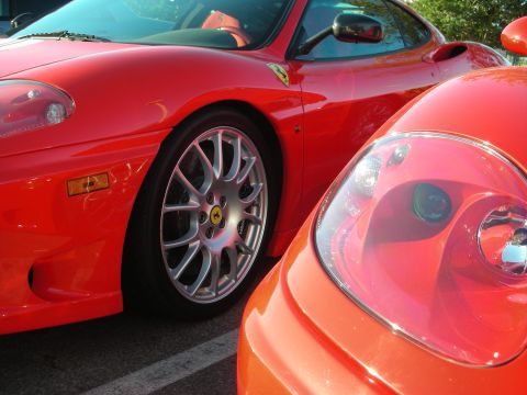 1998 Ford Crown Victoria - Two red Ferraris parked nose to tail, showing a prancing-horse fender shield and a silver multi-spoke wheel.