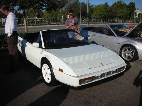 1998 Ford Crown Victoria - white Ferrari Mondial convertible parked front three-quarter with the prancing-horse badge, people standing alongside.