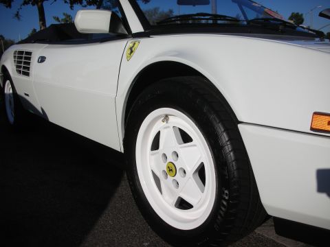 1998 Ford Crown Victoria - Close-up of a white Ferrari's front fender shield and a white wheel fitted with a yellow Ferrari center cap.