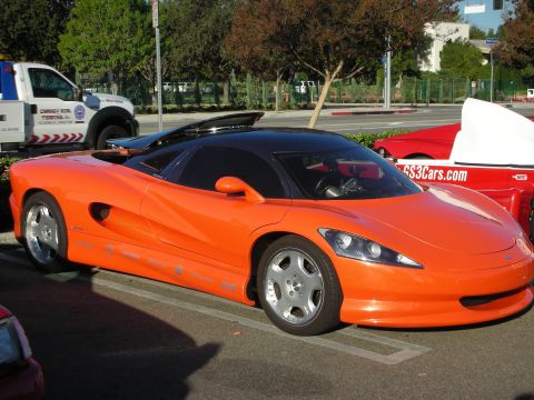 1998 Ford Crown Victoria - orange custom mid-engine sports car parked in a lot, with a red car marked GS3Cars.com beside it.