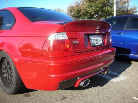 1998 Ford Crown Victoria - Rear three-quarter of a red coupe with dual round tailpipes, a BMW roundel and a California plate, parked beside a blue car.