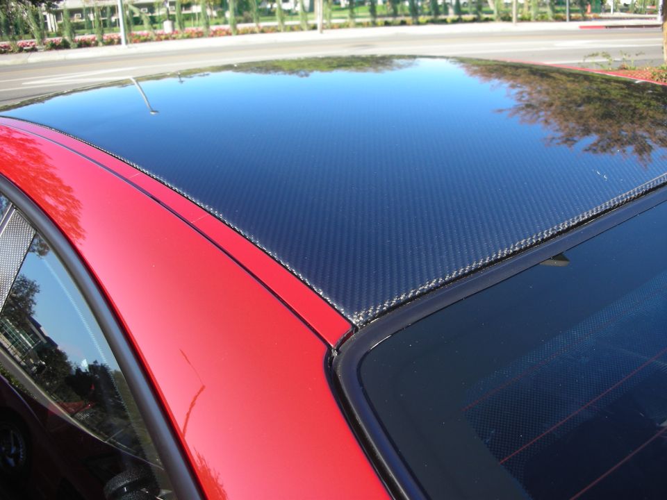 Carbon-fiber roof panel on a red coupe seen from above in sunlight