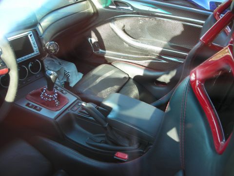 1998 Ford Crown Victoria - car interior with a black leather manual shifter, carbon-fiber door panel and a red-padded roll bar behind the seats.