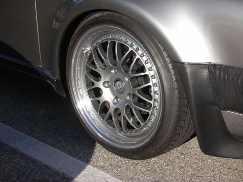 1998 Ford Crown Victoria - polished-lip multi-spoke wheel with a low-profile tire sits under the gray fender of a parked car.