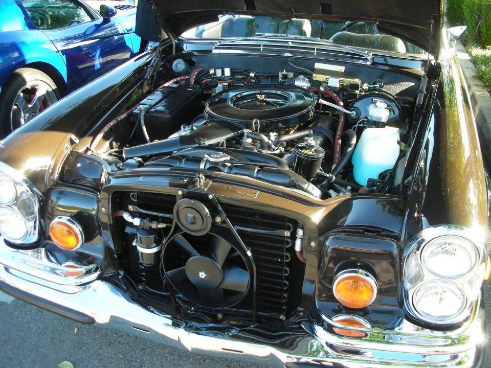 Detailed Mercedes V8 engine bay in a black classic sedan, hood up