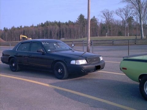 2000 Ford Crown Victoria - A black 2000 Ford Crown Victoria is parked at a drag strip next to a green car.
