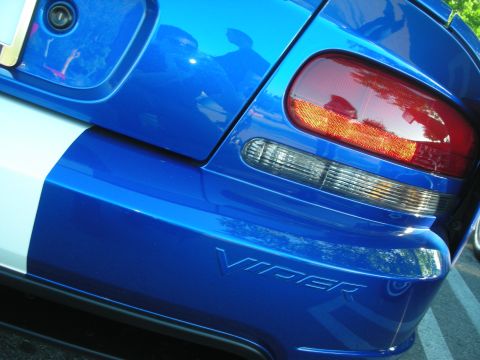 1998 Ford Crown Victoria - Close-up of a blue Dodge Viper's rear quarter showing the 'VIPER' script, white stripe and amber-and-clear taillight.