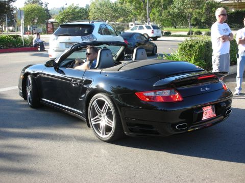 1998 Ford Crown Victoria - black Porsche 911 Turbo cabriolet with the top down and silver alloy wheels, parked at a car gathering with onlookers nearby.