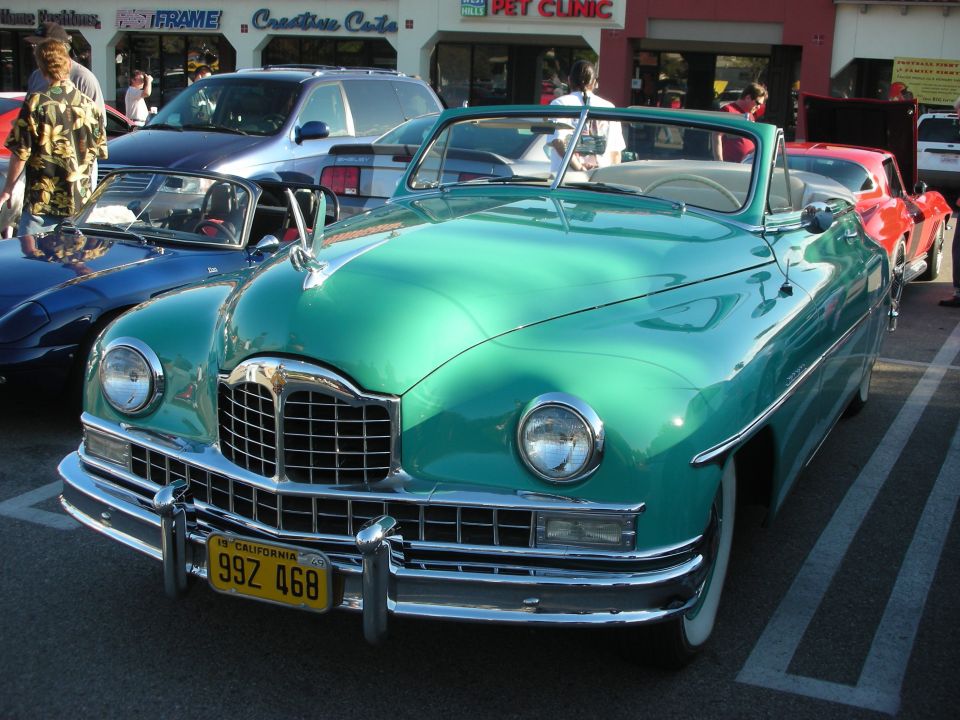 Green vintage 1949 convertible with chrome grille and California plate at a car show