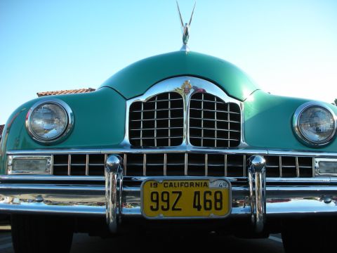 1998 Ford Crown Victoria - Head-on view of a teal-green 1949 vintage car with twin headlights, chrome bumper and a yellow California license plate.