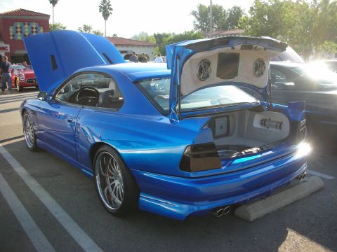 1998 Ford Crown Victoria - blue BMW 8 Series coupe shown rear three-quarter with both the hood and trunk open revealing a stereo install.