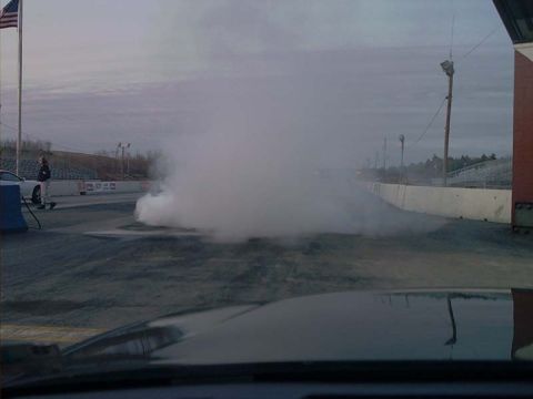 2000 Ford Crown Victoria - Drag strip scene with a car performing a burnout, creating a massive smoke plume.