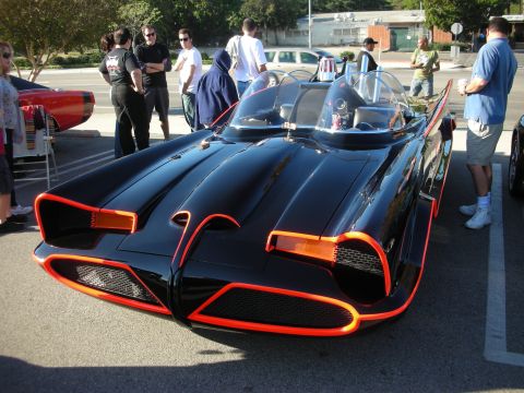 1998 Ford Crown Victoria - black bubble-canopy 1960s-style Batmobile with glowing red pinstripe trim, parked among spectators at a car meet.