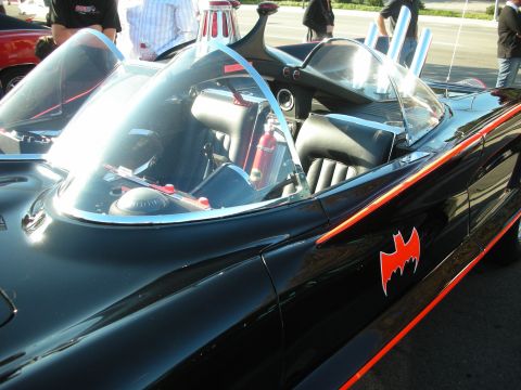 1998 Ford Crown Victoria - Side view of a black Batmobile replica showing a red bat emblem on the body, twin bubble canopies and a fire extinguisher in the cockpit.