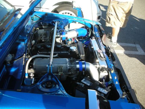 1998 Ford Crown Victoria - Open engine bay of a blue car showing a forced-induction setup with blue piping and a valve cover marked TWIN CAM 16 VALVE.
