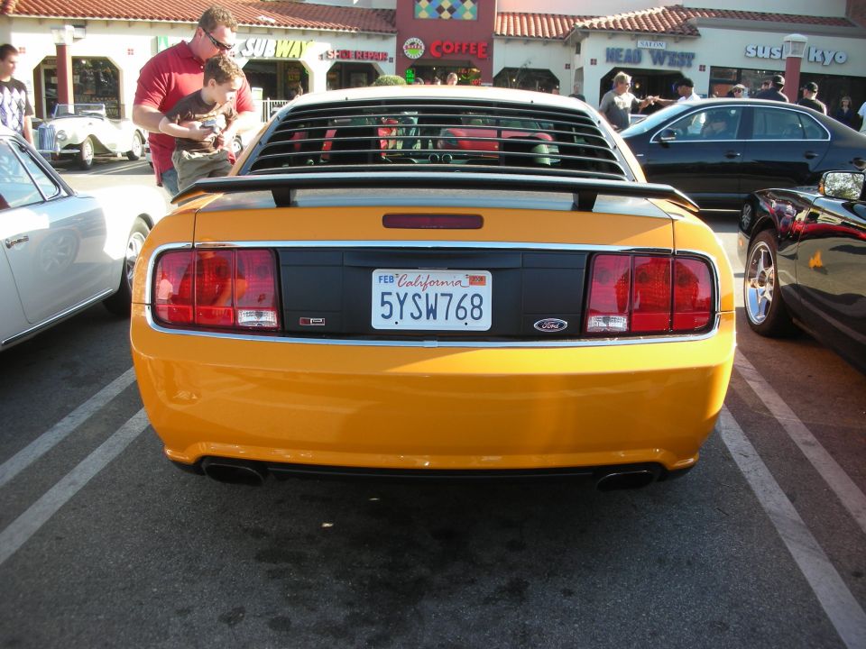 Rear of orange-yellow Ford Mustang with window louvers and plate 5YSW768
