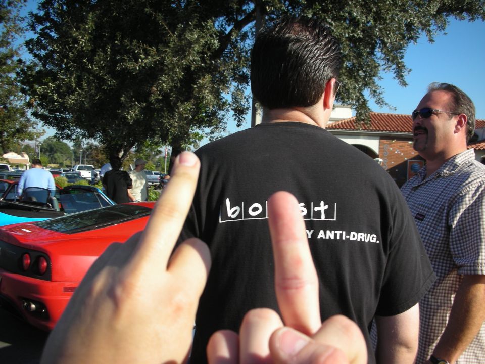 Man from behind in black 'boost' anti-drug T-shirt with two people pointing