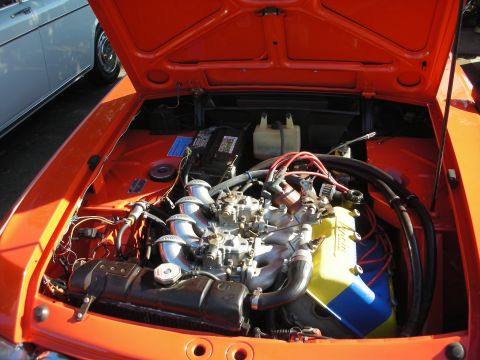 1998 Ford Crown Victoria - Close-up of an orange car's engine bay showing twin side-draft carburetors, an intake manifold, and a yellow component.