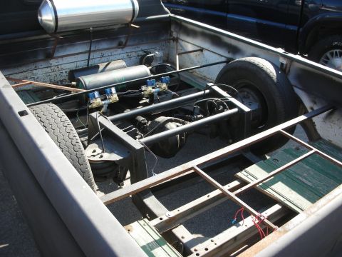 1998 Ford Crown Victoria - The chassis of a truck is shown with air suspension components, and another vehicle is visible in the background.