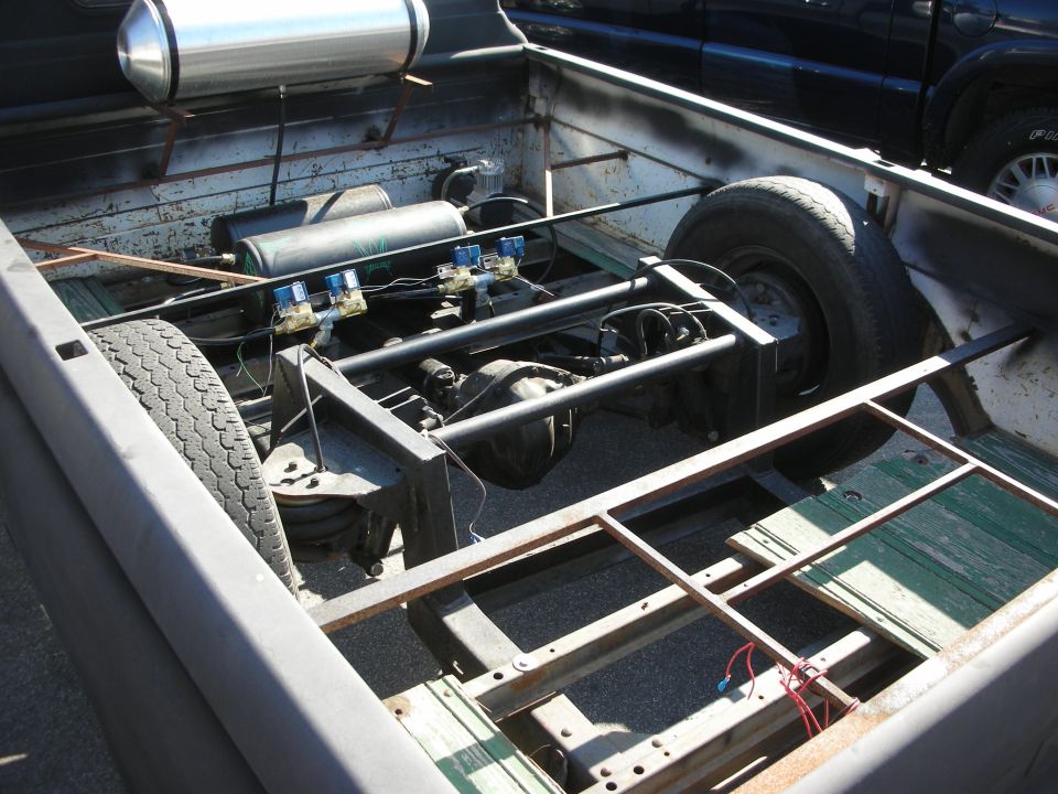 Bare truck frame on a flatbed showing rear axle and air tank