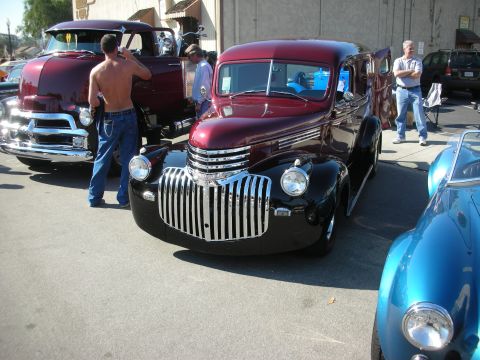 1998 Ford Crown Victoria - A classic maroon and black sedan is parked next to a burgundy pickup truck and a blue sports car.