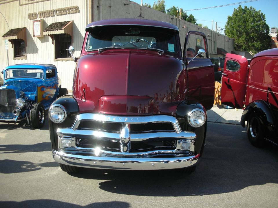 Front of maroon 1950s Chevrolet pickup with chrome grille, door open