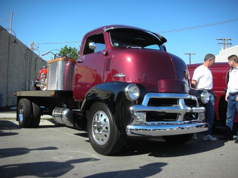 1998 Ford Crown Victoria - A custom flatbed truck, likely from the 1950s, is parked with a motorcycle secured on its bed.