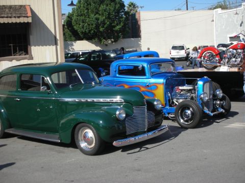 1998 Ford Crown Victoria - Two classic cars, a green sedan and a blue hot rod, are parked side-by-side at an outdoor event.