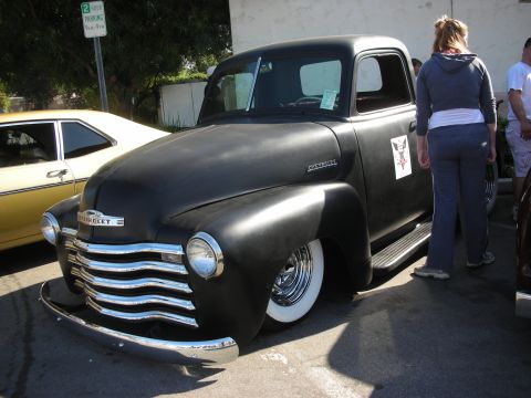 1998 Ford Crown Victoria - A classic black Chevrolet truck is parked outdoors, with a yellow car visible to its left.