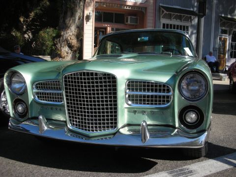 1998 Ford Crown Victoria - A vintage green automobile with a prominent chrome grille is parked on a street.