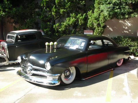 1998 Ford Crown Victoria - Customized hot rod with unique hood exhaust pipes and lowered stance at a car show.