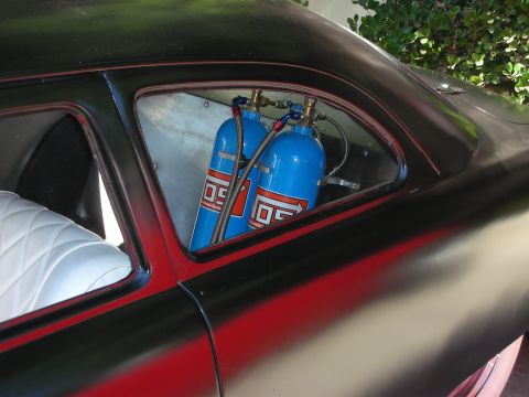 1998 Ford Crown Victoria - The interior of a car is visible, two blue nitrous oxide tanks and white diamond-stitched upholstery.
