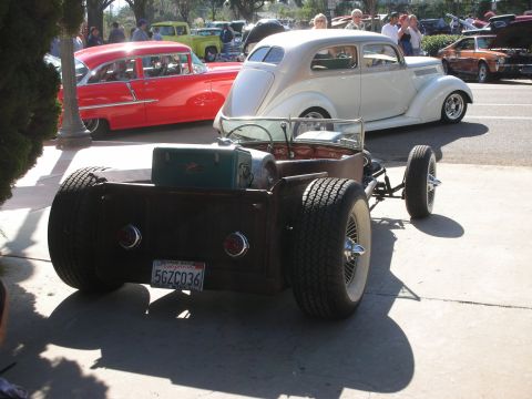 1998 Ford Crown Victoria - A custom-built rat rod is parked outdoors, with other classic cars in the background.