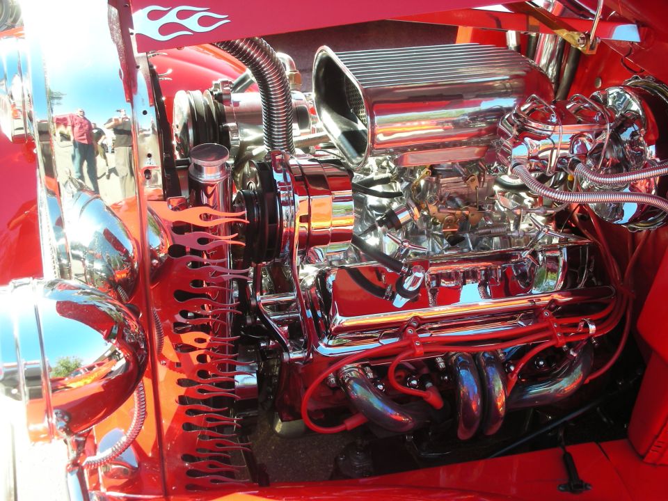 Heavily chromed supercharged V8 engine in a red hot rod with flame detailing