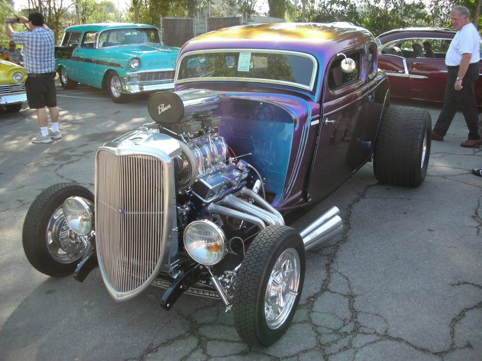 Purple flame-painted 1934 Ford coupe hot rod with chrome grille at a car show