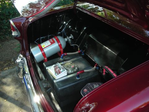 1998 Ford Crown Victoria - The trunk of a car contains a nitrous oxide tank and a fuel cell, along with various hoses and wiring.
