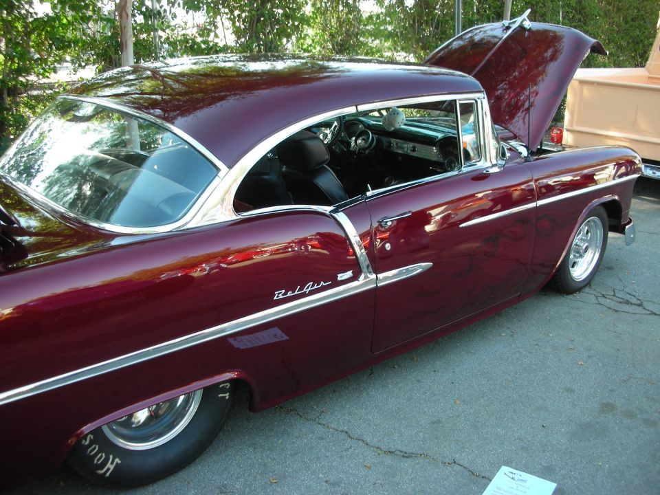 Maroon 1955 Chevrolet Bel Air hardtop with hood open at a car show