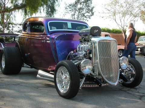 1998 Ford Crown Victoria - A custom hot rod with a prominent V8 engine and iridescent paint is parked outdoors.