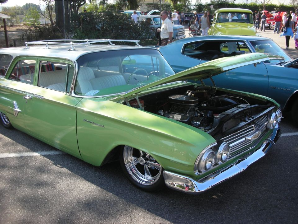 Green 1960 Chevrolet station wagon with roof rack and open hood at a show