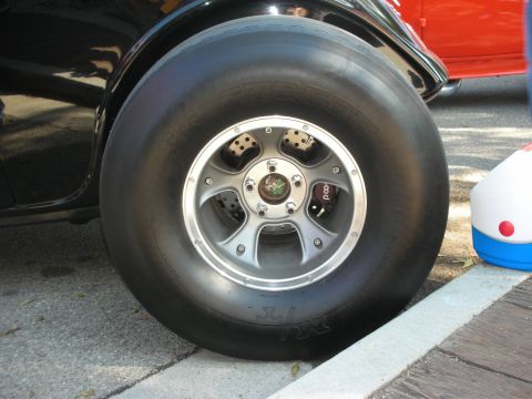 1998 Ford Crown Victoria - Close-up of a large tire and custom wheel on a vehicle, with another car in the background.