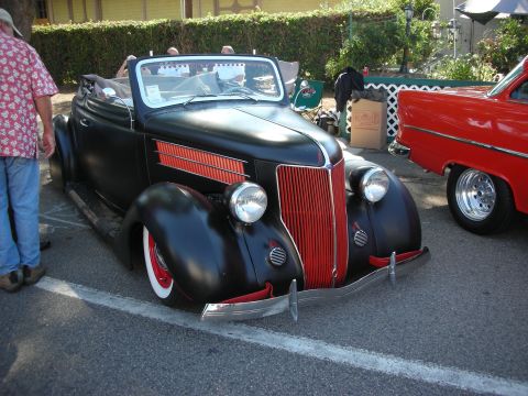 1998 Ford Crown Victoria - Custom black convertible hot rod with red accents, parked beside a red classic car.