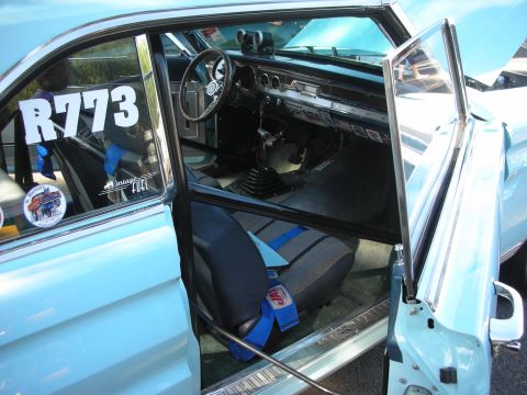 1998 Ford Crown Victoria - Classic car interior with roll cage and racing seat, visible racing numbers and stickers on the window.