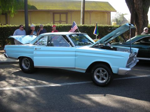 1998 Ford Crown Victoria - A light blue classic coupe is displayed with its hood and trunk open, alongside another vehicle.