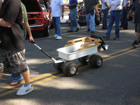 1998 Ford Crown Victoria - A custom wagon is pulled along a street with other vehicles and people in the background.