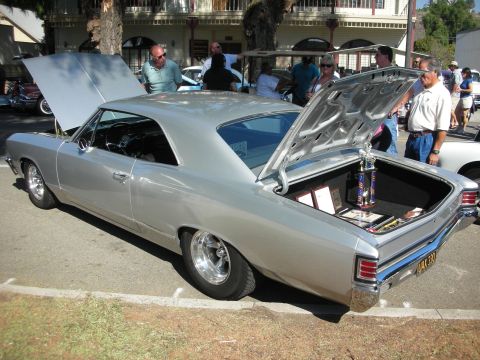 1998 Ford Crown Victoria - A silver 1967 coupe is displayed with its hood and trunk open, revealing trophies inside the trunk.