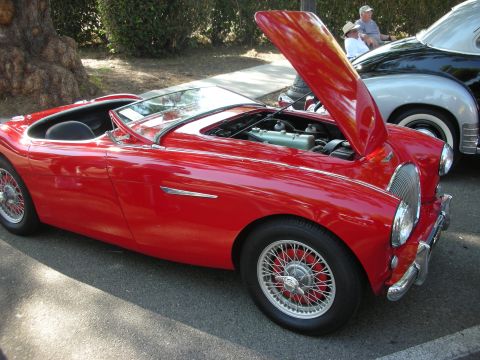 1998 Ford Crown Victoria - A classic red convertible is displayed with its hood open, parked next to another vintage vehicle.