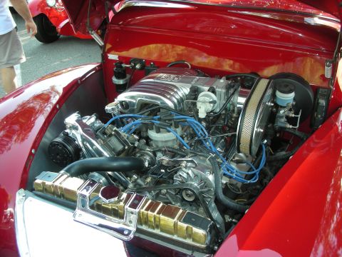 1998 Ford Crown Victoria - The engine bay of a red classic car is visible, chrome accents and a prominent V8 engine.