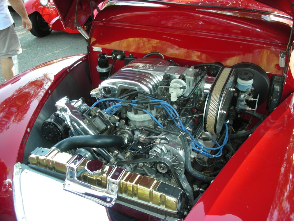 Chrome supercharged V8 engine with blue wires in red custom car